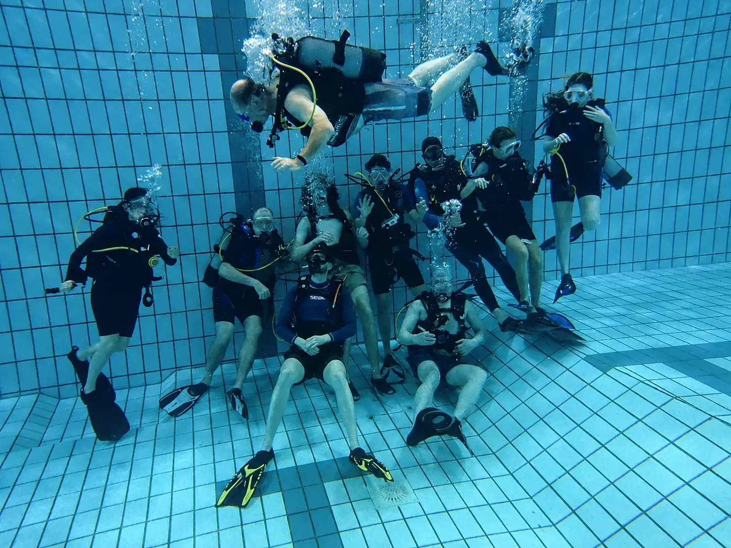 Groep HiDive-duikers met persluchtuitrusting onder water in het zwembad